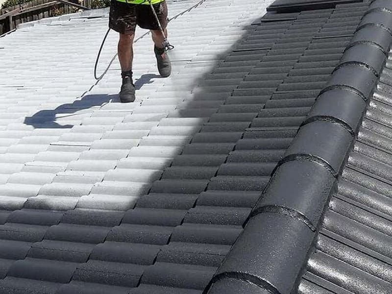 Worker spray-painting roof tiles